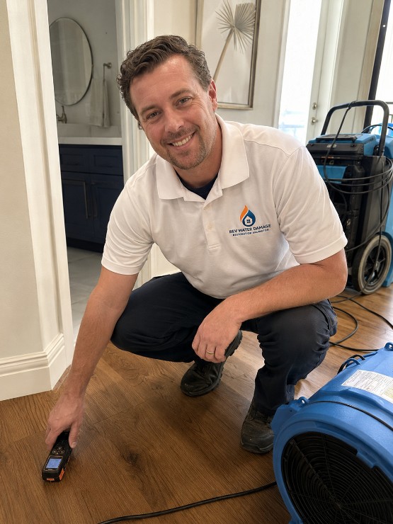 Technician taking moisture reading on hardwood floor